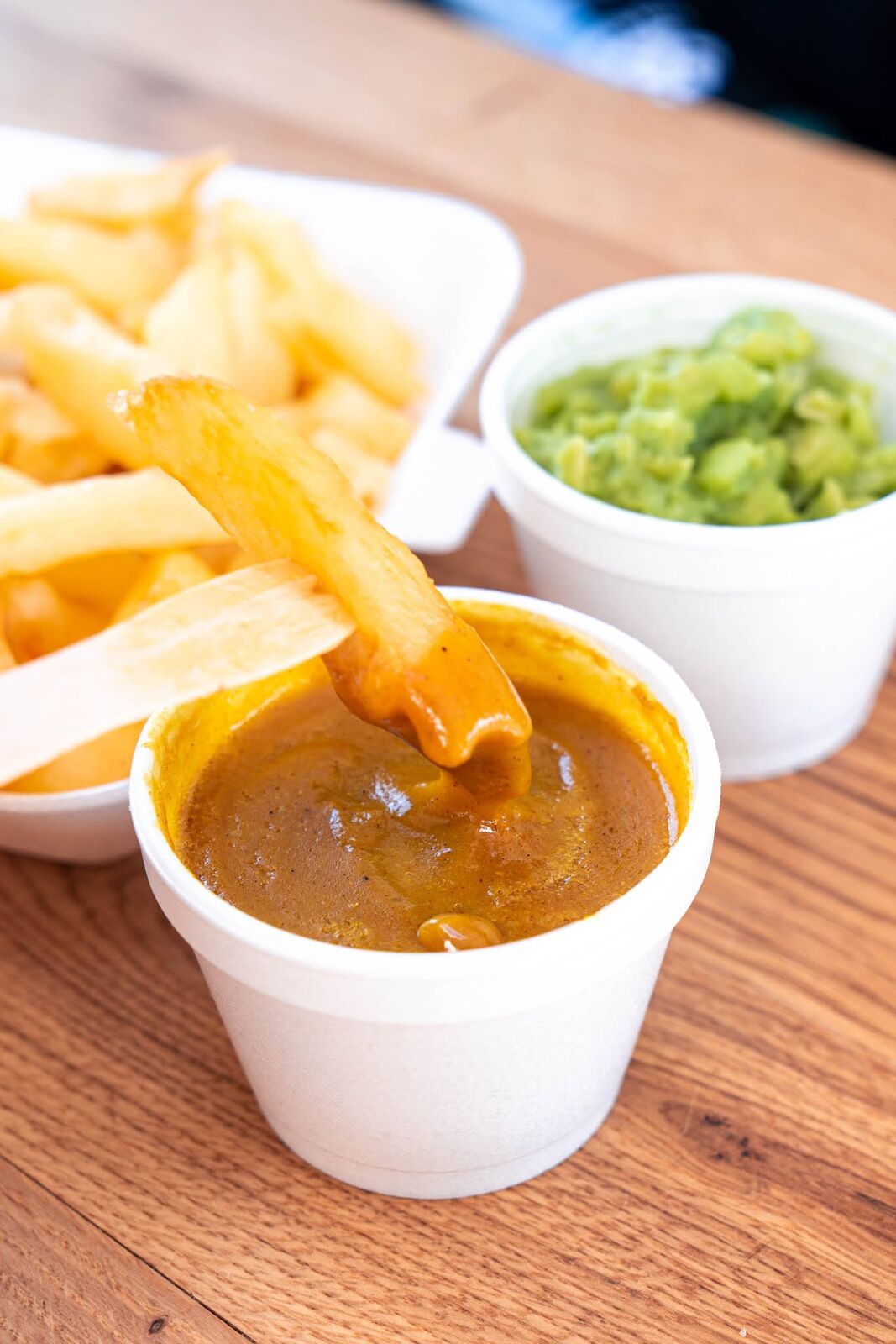 Chips dipped in curry sauce with a pot of mushy peas