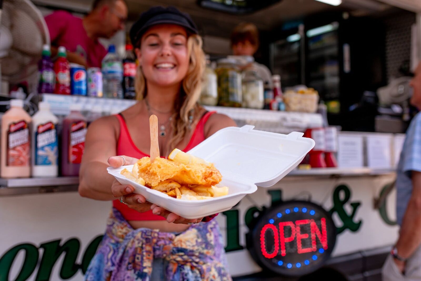 Happy customer holding up a box of fish and chips in front of the van
