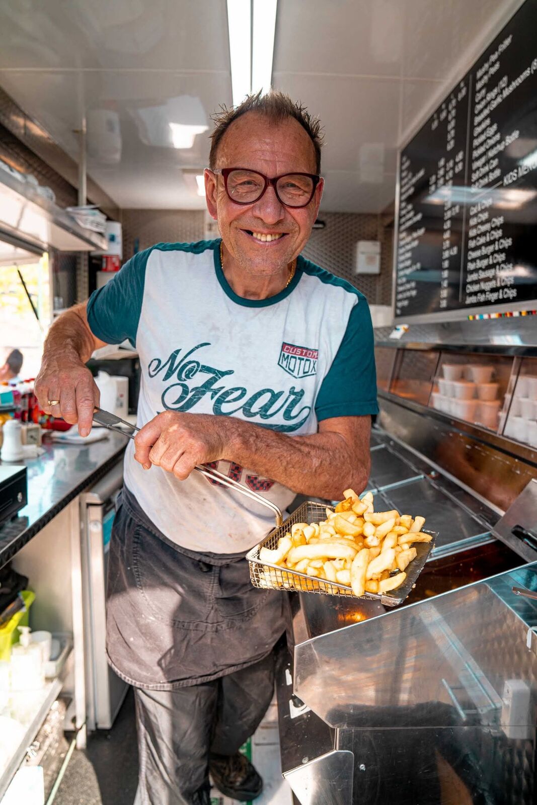David lifting a basket of freshly fried chips inside the van